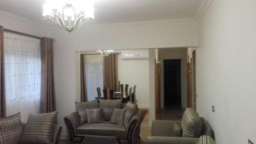 een woonkamer met stoelen en een kroonluchter bij Cozy fully well furnished apartment for rent in Mesaha Square - Dooki in Caïro