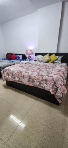 a bedroom with a bed with a floral bedspread at jason apartment in Abu Dhabi