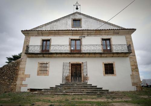 an old white building with a balcony and stairs at CASA RURAL PALACIO CONDE DE ALDANA con piscina entre encinares y dehesas in Terradillos