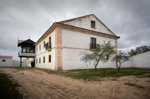 a large white building on a dirt road at CASA RURAL PALACIO CONDE DE ALDANA con piscina entre encinares y dehesas in Terradillos