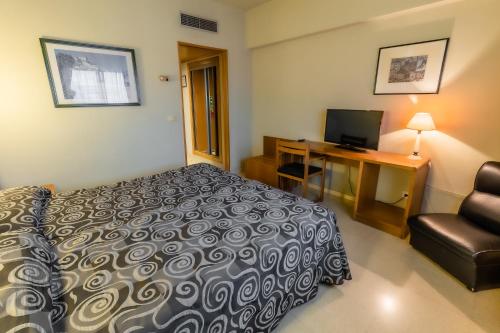 a hotel room with a bed and a desk and a chair at Hotel Alhama in Cintruénigo