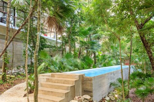 a swimming pool in the middle of a garden with trees at Nido De Tortuga Akumal With Beach Access And Private Jacuzzi in Akumal