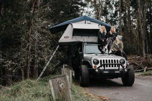 Un gruppo di persone seduti sul tetto di una jeep di Zazu Campers a Kahului