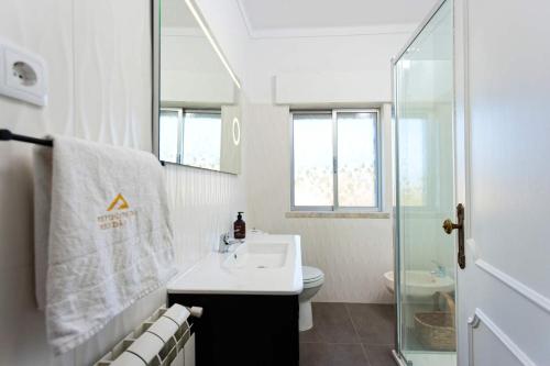 a white bathroom with a sink and a shower at Quinta Refúgios do Rio Dão in Mangualde