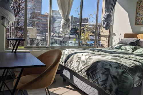 Schlafzimmer mit einem Bett, einem Tisch und einem Fenster in der Unterkunft CityZen escape: blackout ready in Johannesburg