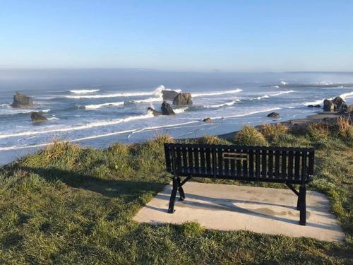 a bench sitting on a sidewalk near the ocean at Table Rock Motel in Bandon