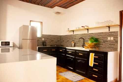 a kitchen with black cabinets and a white refrigerator at VILLA TIARÉ DIEGO in Antsakomboena