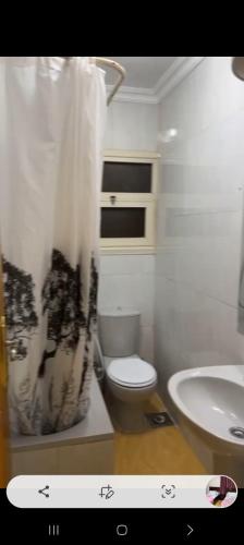 ein Badezimmer mit einem weißen WC und einem Waschbecken in der Unterkunft عباس العقاد in Kairo