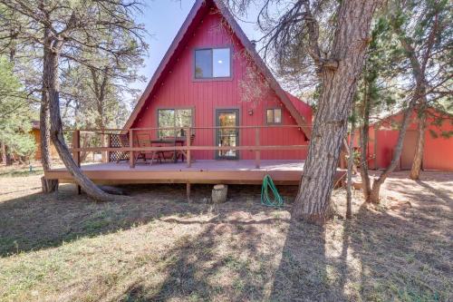 a red house with a porch and a tree at Decks and Fire Pit Rustic-Modern Overgaard Cabin! in Overgaard
