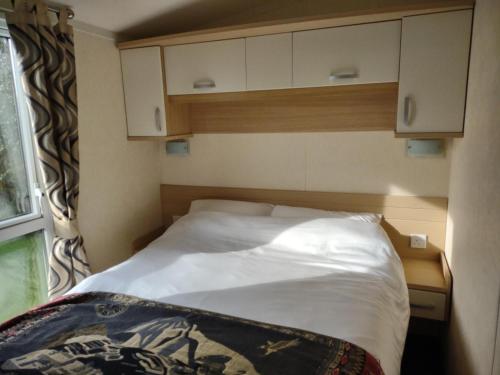 een kleine slaapkamer met een bed met witte lakens en een raam bij Ann & Rogers Retreat Skipsea Sands in Ulrome