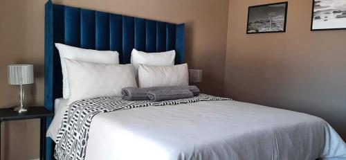 a large bed with a blue headboard and white pillows at Soma Guesthouse in Groblersdal