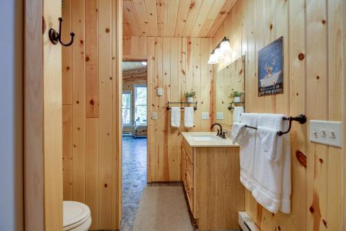La salle de bains est pourvue de murs en bois, de toilettes et d'un lavabo. dans l'établissement Lakefront Paradise with Private Boat Dock and Patio, à Deer River