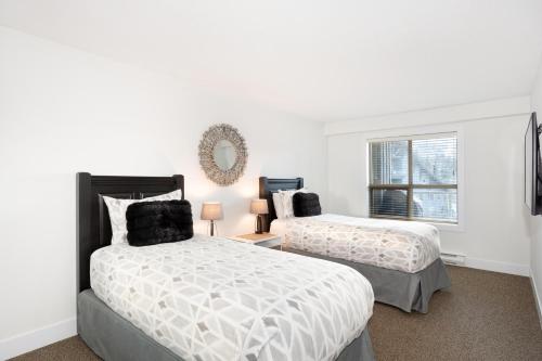 1 dormitorio con 2 camas y ventana en Aspens 466 - Pool & 3 Hot Tubs, BBQ, Gym, Close to Bike Trails - Whistler Platinum, en Whistler