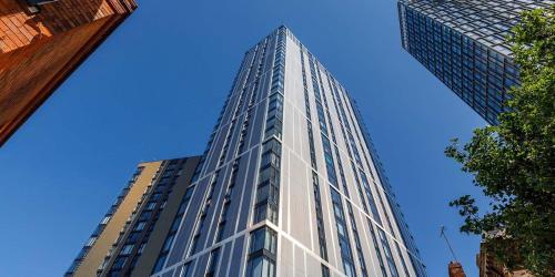 伯明罕的住宿－Luxury 2 Bedroom Apartment, Broad street Birmingham，一座高大的玻璃建筑,背后是蓝天