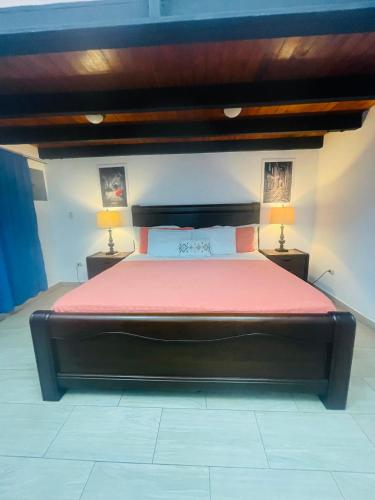 a bedroom with a large bed with red sheets and two lamps at Cabañas Marroquin 1 in Copan Ruinas