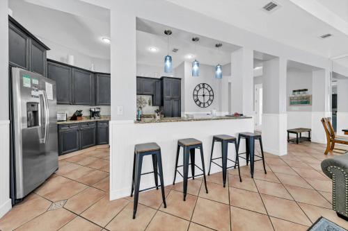 a kitchen with black cabinets and bar stools at Our Destiny in Dunes of Destin - Is a 4BR with Private Pool and close Beach Access in Destin
