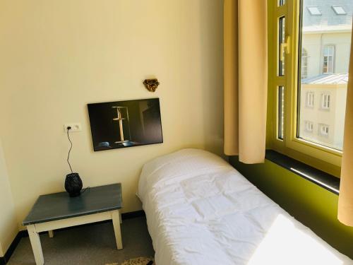 a small bedroom with a bed and a window at De Lotuspoort met Mihr's B&B in de Abdij van Bornem in Bornem