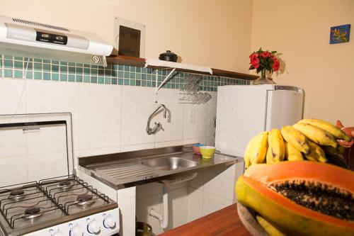 a kitchen with a stove and a bunch of bananas at Trindade Hospeda - Casinha Praia Ranchos in Trindade