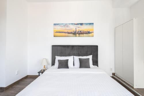 a bedroom with a large white bed and a painting on the wall at Downtown Victoria Apartments By CityBookings in Bucharest