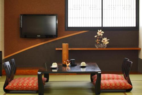 a dining room with a table and two chairs and a tv at Hotel Chatelet Inn Kyoto in Kyoto