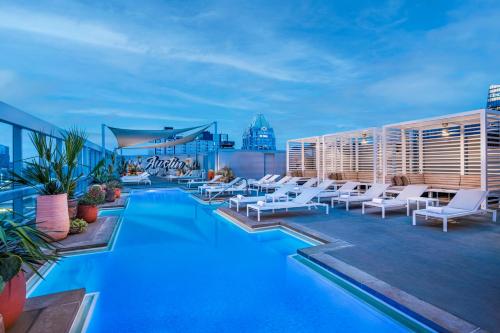 a pool on the rooftop of a building with white chairs at Omni Austin Hotel Downtown in Austin
