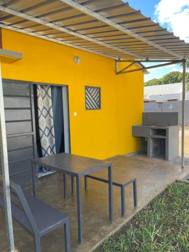 un patio con tavolo, sedie e parete gialla di STUDIO TIARÉ DIEGO a Antsakomboena