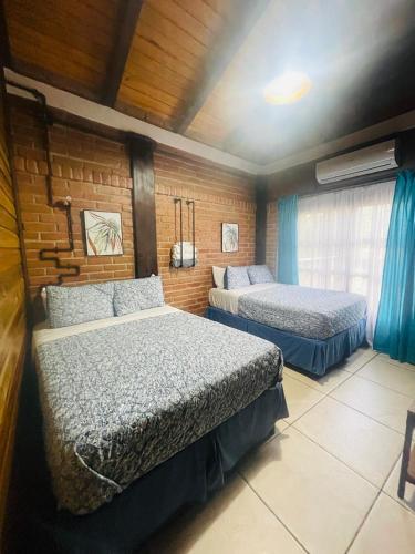 a bedroom with two beds and a brick wall at Cabañas Marroquin 2 in Ostumán