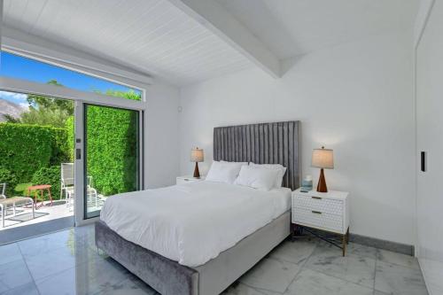 ein weißes Schlafzimmer mit großem Bett und Balkon in der Unterkunft Palm Springs Luxury Home With Pool and Next to Downtown & Airport in Palm Springs