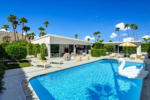 a swimming pool with a swan in front of a house at Palm Springs Luxury Home With Pool and Next to Downtown & Airport in Palm Springs