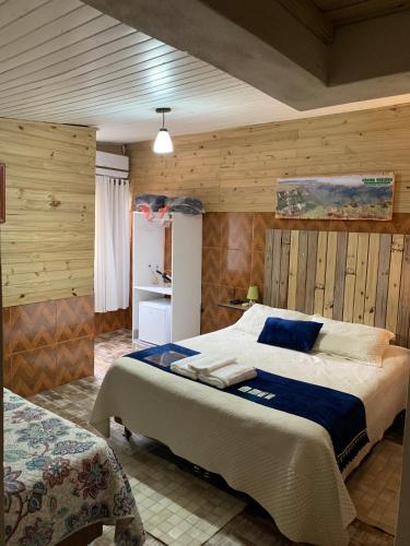 a bedroom with a large bed and wooden walls at Pousada Deck 950 - Cambará do Sul in Cambará