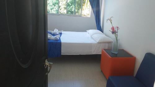 Un pequeño dormitorio con una cama y un jarrón de flores en Tropical Resort Tocaima, en Tocaima