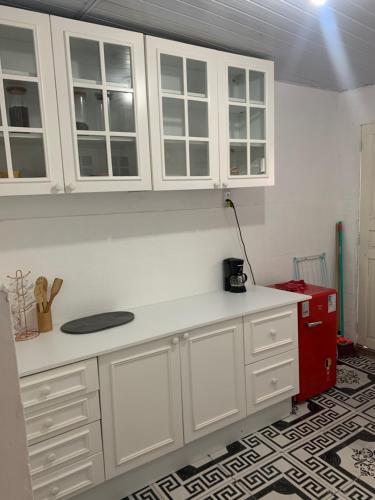a kitchen with white cabinets and a red refrigerator at Casa simples in Belém