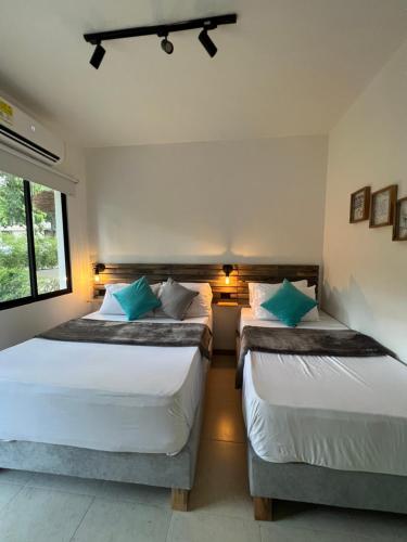two beds in a small room with a window at HOTEL 9.5 SAN FERNANDO in Cali