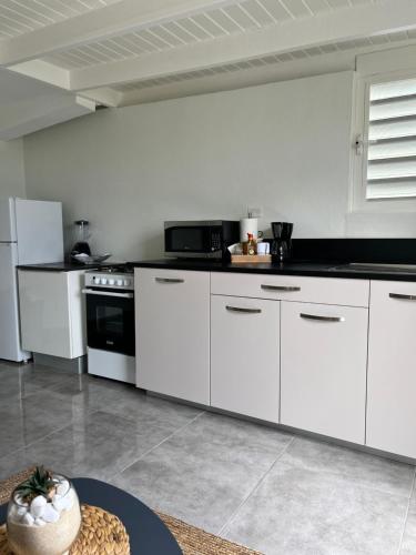 a kitchen with white cabinets and a black counter top at Jm.HouseSxm in Koolbaai