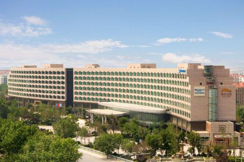 a large office building in a city with trees at Wyndham Qingdao in Qingdao