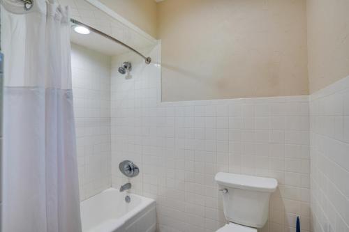 a white bathroom with a toilet and a shower at Lakefront Winter Haven Retreat Hot Tub and Patio! in Winter Haven