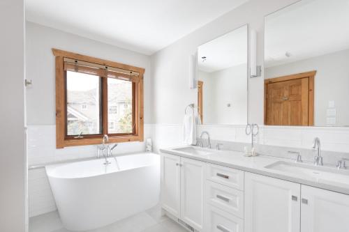 a white bathroom with two sinks and a bath tub at Meadow Green Chalet - Family Chalet, Golf Course, Hot Tub, BBQ, Garden - Whistler Platinum in Whistler