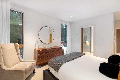 1 dormitorio con cama, silla y espejo en Kadenwood 2927 - Luxury Mountain View Chalet, Jacuzzi, Media Room - Whistler Platinum en Whistler