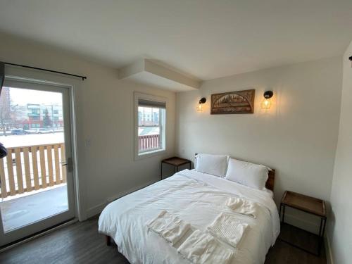 エドモントンにあるLovely 1 Bedroom Condo Free Parking And Balconyのベッドルーム(白いベッド1台、バルコニー付)