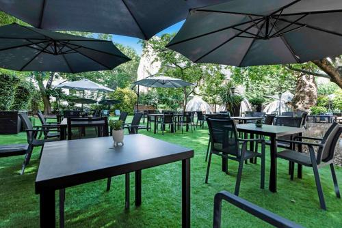 un gruppo di tavoli e sedie con ombrelloni di Doubletree By Hilton London Kensington a Londra