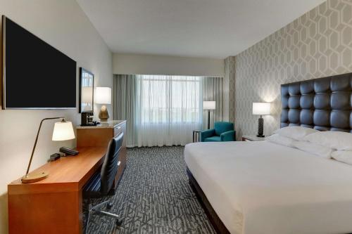 a hotel room with a bed and a desk with a television at Drury Plaza Hotel Dallas Arlington in Arlington