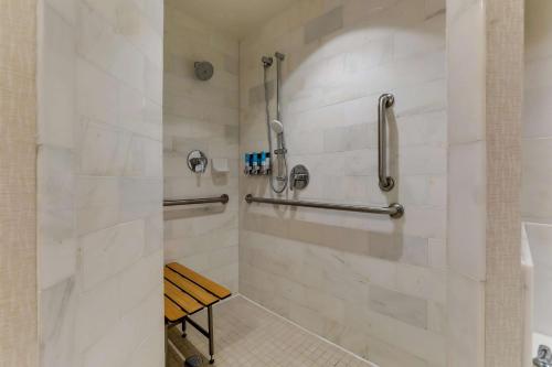 La salle de bains est pourvue d'une cabine de douche avec un banc. dans l'établissement Drury Plaza Hotel Dallas Arlington, à Arlington