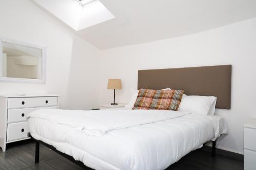 a white bedroom with a large bed and a mirror at Hosting Dreams Attics - Duomo in Milan