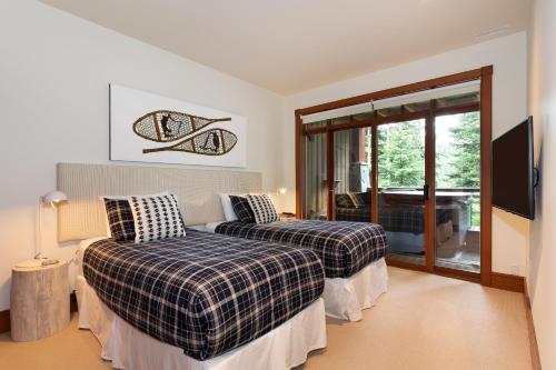 een slaapkamer met 2 bedden en een glazen schuifdeur bij Taluswood The Lookout 5 - Secluded Chalet with Hot Tub & Incredible Views - Whistler Platinum in Whistler