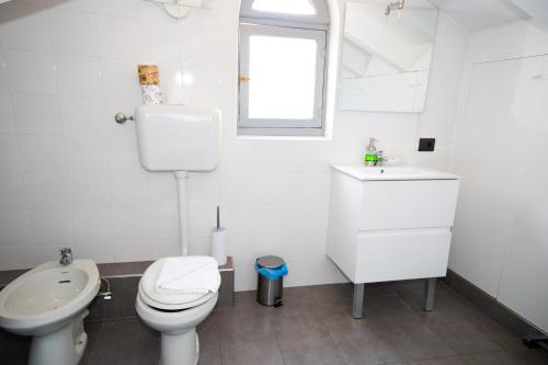 a white bathroom with a toilet and a sink at Hosting Dreams Attics - Duomo in Milan