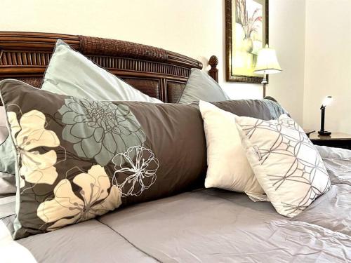 een bed met verschillende kussens erop bij 9055 Resort Gem Condo-3 bed/2ba in Kissimmee