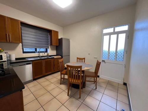 Una cocina con mesa y sillas y una cocina con ventana. en The Hideaway Retreat, en Santo da Serra