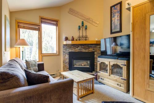 a living room with a couch and a fireplace at Winter Park Ski-InandSki-Out Condo with Mountain Views in Winter Park