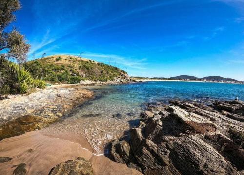 Blick auf einen Strand mit Felsen und das Meer in der Unterkunft Pousada Paraíso das Conchas na praia do Peró Cabo Frio RJ in Cabo Frio