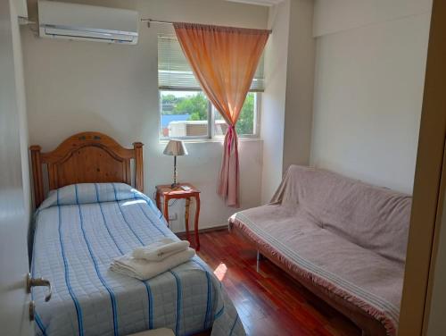 a bedroom with a bed and a couch and a window at Apreciando la montaña in Mendoza